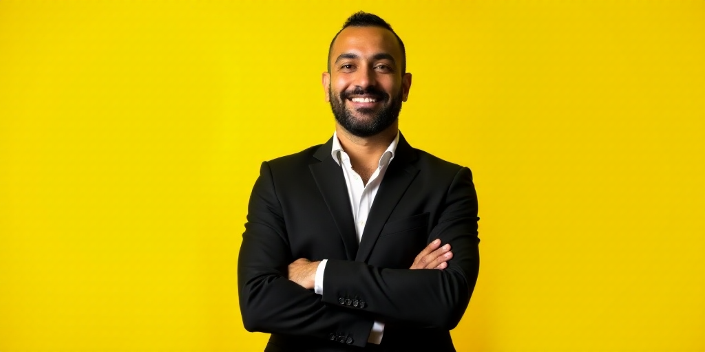 a man in a suit standing with his arms crossed and smiling at the camera with his arms crossed, with