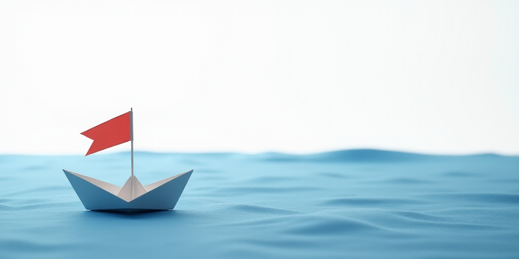 a paper boat and a flag on a blue cloth covered surface with a white sky in the background and a whi