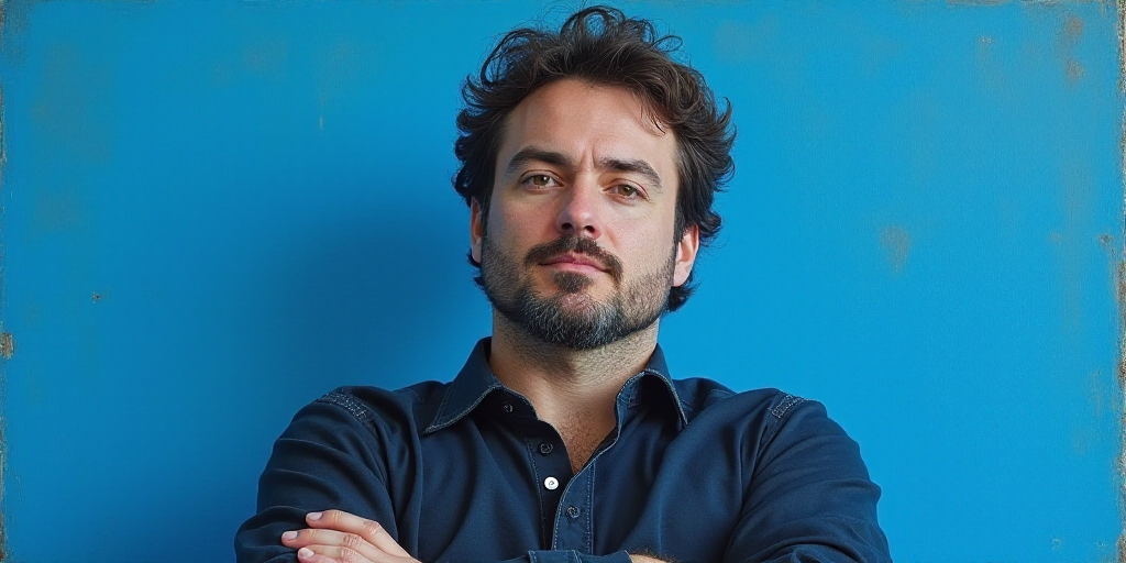 a man with his arms crossed standing in front of a blue background with a black and white photo of h