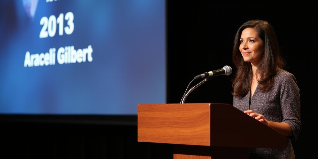 a woman standing at a podium with a microphone in her hand and a screen behind her behind her that s