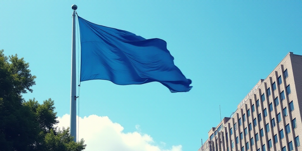 a blue flag flying in the wind next to a tall building with a sky background and trees in the foregr