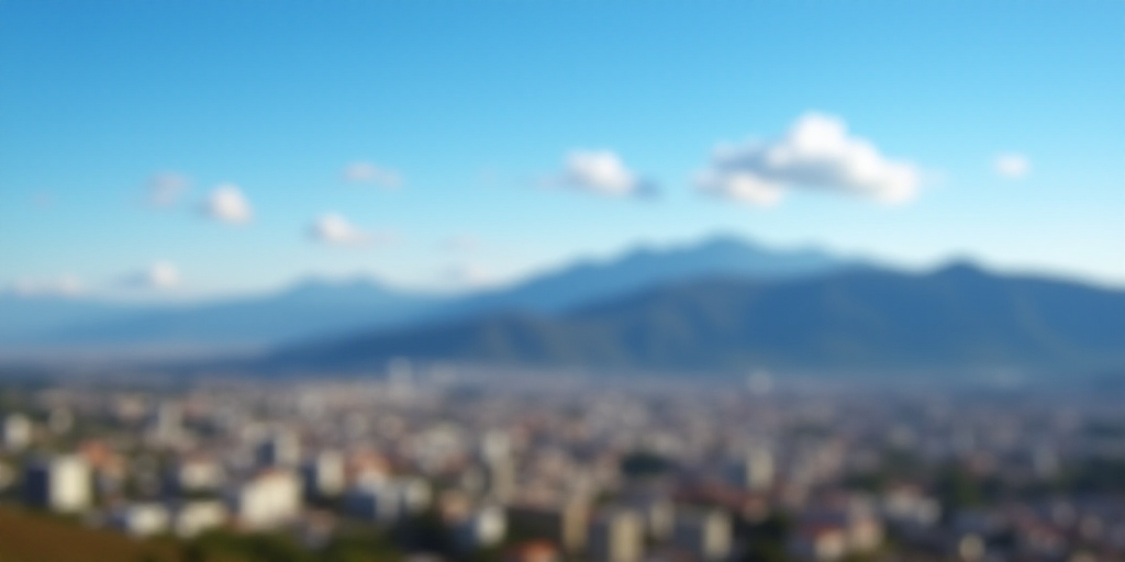 a city with mountains in the background and a blue sky in the foreground with a few clouds in the sk