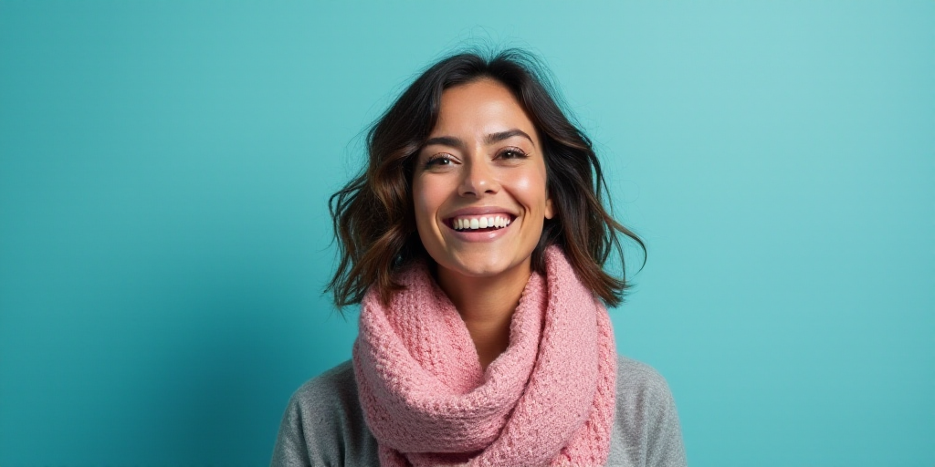 a woman with a scarf on her neck smiling at the camera with a blue background and a black and white