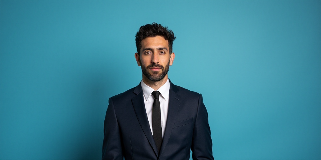a man in a suit and tie standing in front of a blue background with a black and white photo, Alejand