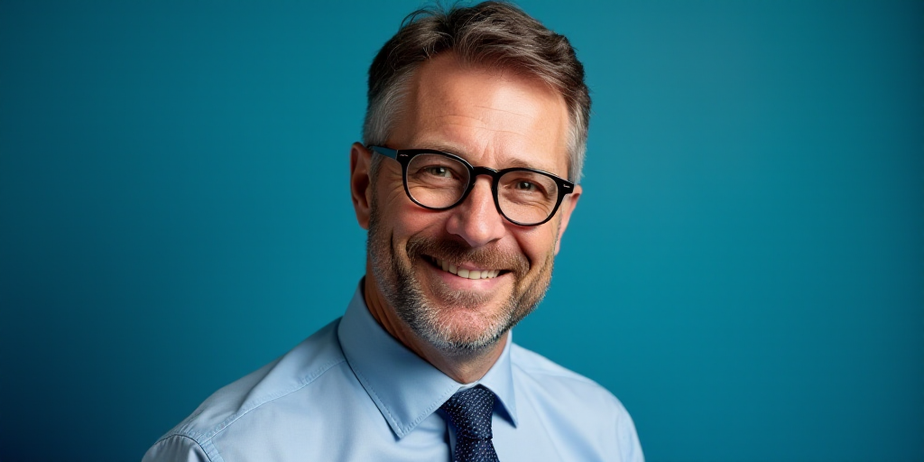 a man with glasses and a tie on his neck is smiling for the camera with a blue background behind him
